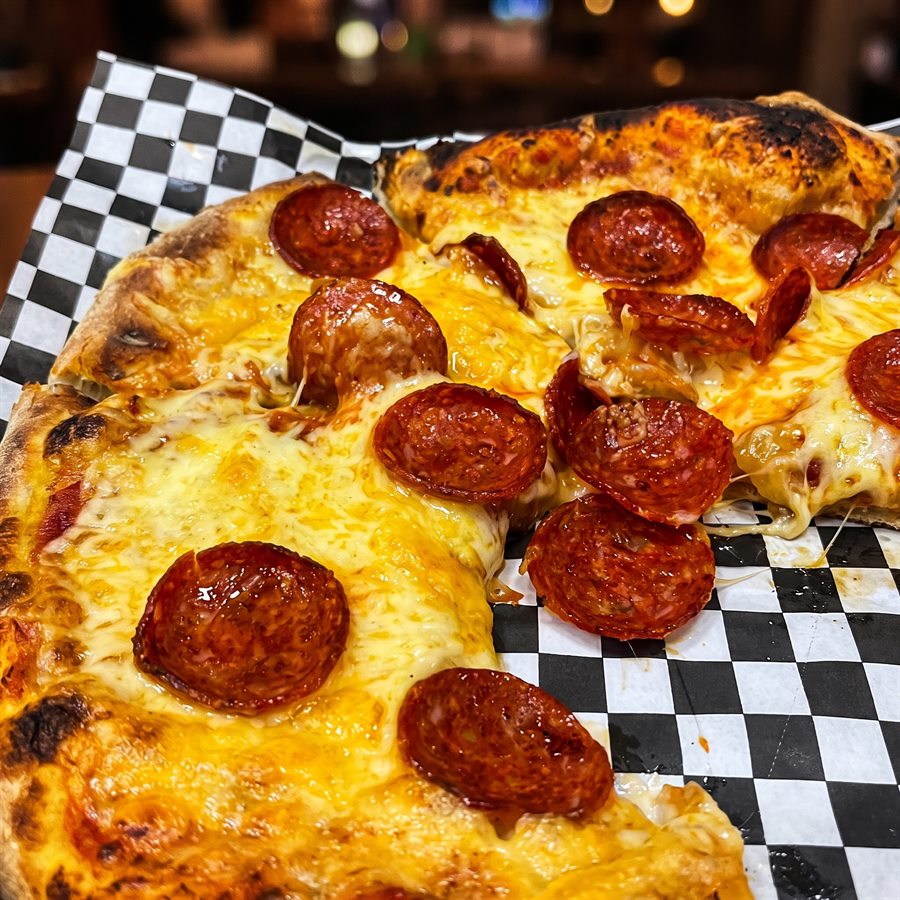 Pizza artesanal de pepperoni con queso derretido sobre papel cuadriculado
